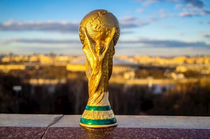 Cup vàng World Cup với hình ảnh 2 người đang nắm giữ Trái Đất